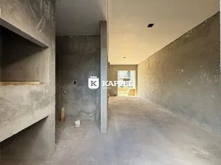Hall de corredor com paredes de concreto aparente e teto cru.