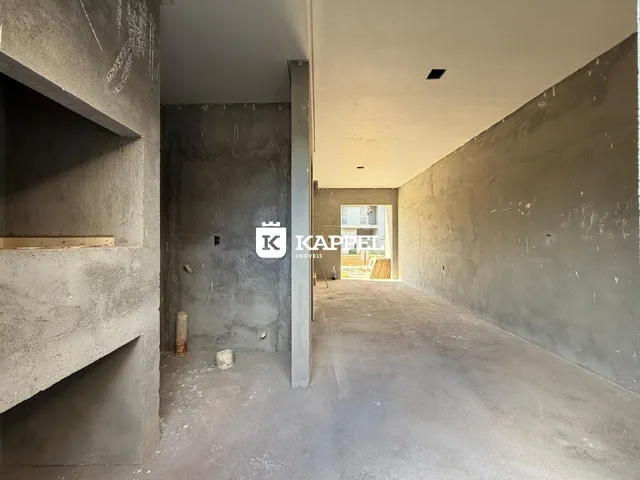 Hall de corredor com paredes de concreto aparente e teto cru.