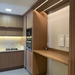 Cozinha moderna com armários de madeira clara e bancadas.