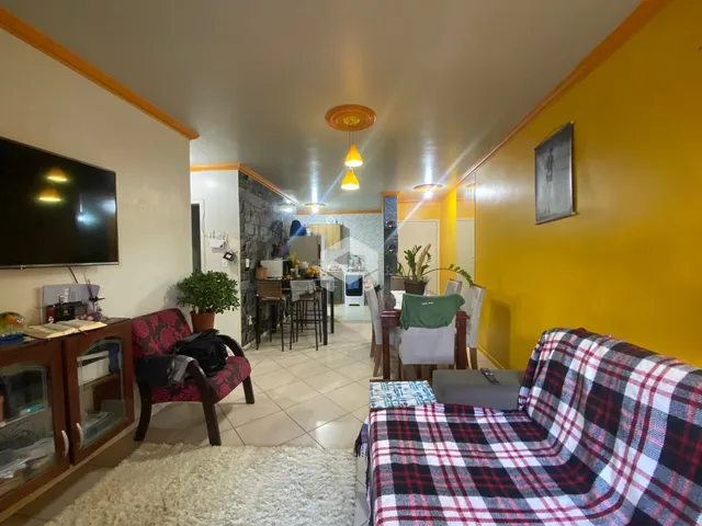 Sala de estar com paredes amarelas e móveis de madeira em um imóvel no Brasil.
