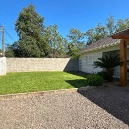 Vista externa de um jardim com gramado e muro de contenção.