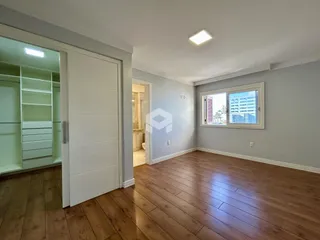 Ambiente interno de uma sala com piso de madeira e janela.