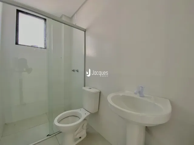 Banheiro com vaso sanitário e pia brancos.