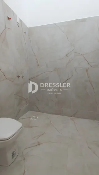 Foto de um ambiente interno com revestimento em mármore e vaso sanitário.