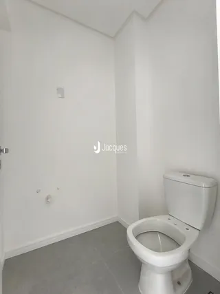 Foto de um banheiro interno com piso cinza claro e vaso sanitário branco.
