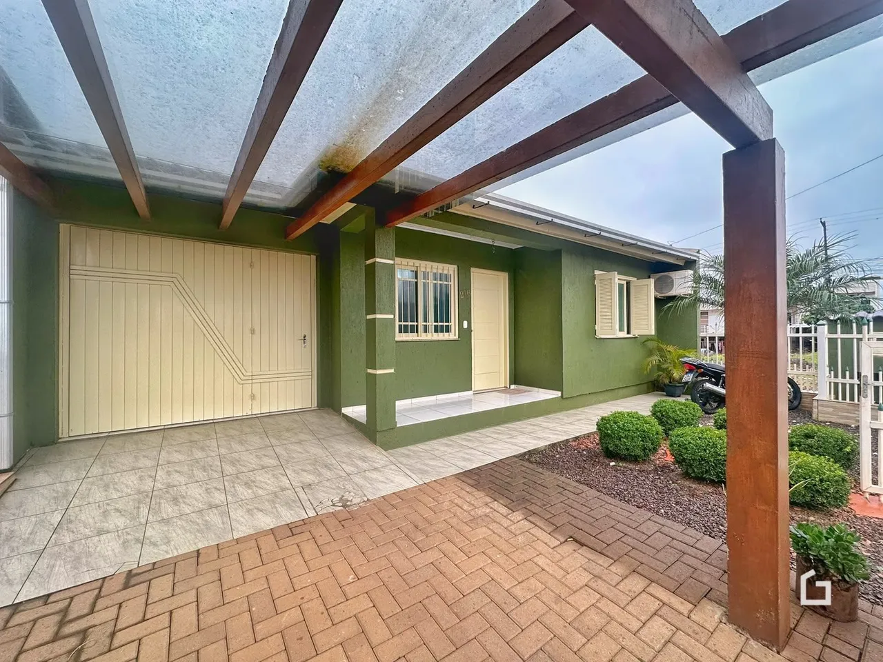 A fachada de uma residência verde com garagem e área externa.