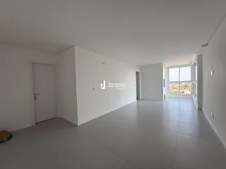 Ambiente interno de uma sala ampla com piso claro e paredes brancas.