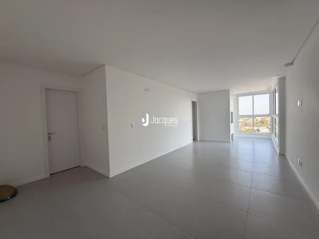 Ambiente interno de uma sala ampla com piso claro e paredes brancas.