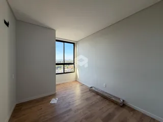 Interior de uma sala com piso de madeira e vista da cidade.
