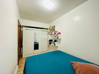 Quarto com cama azul e guarda-roupa branco em ambiente claro.