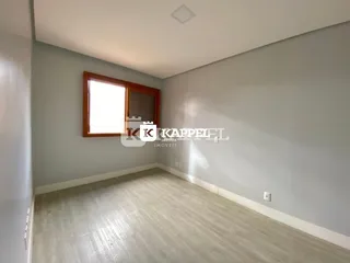 Foto de um cômodo interno com piso de madeira clara e uma janela.