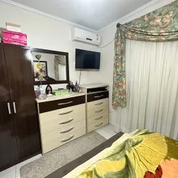 Quarto com armário de madeira e cortinas brancas.