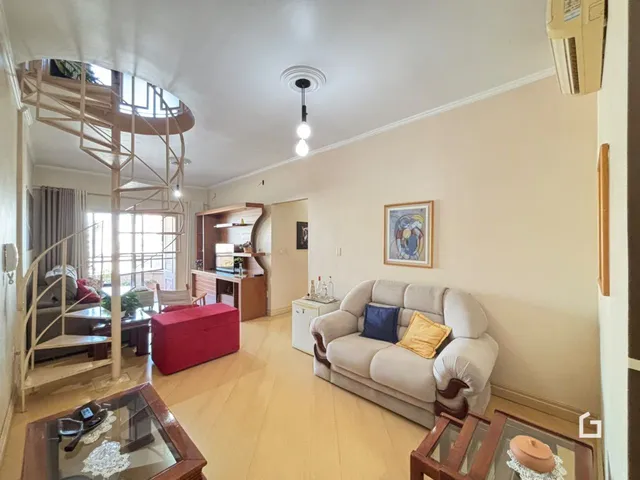 Sala de estar com piso de madeira e escadaria em um ambiente claro.