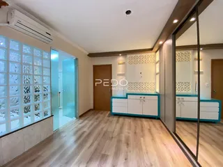 Sala de estar com piso de madeira e grandes janelas.