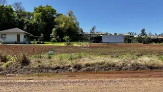 Paisagem rural com casas ao fundo e um campo aberto em primeiro plano.
