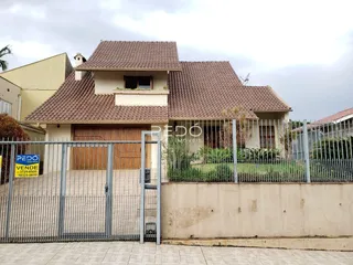 Fachada de uma residência com telhado de telhas e portão de ferro.