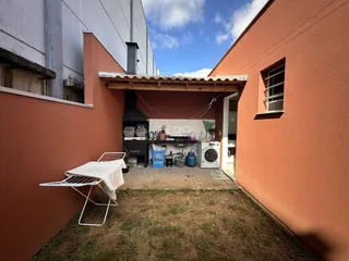 Área externa com gramado e estrutura de madeira entre duas edificações.
