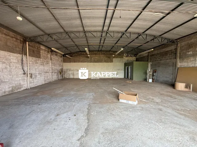 Foto de um espaço amplo e industrial com piso de concreto e estrutura metálica exposta.
