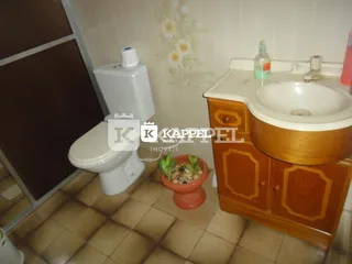 Banheiro com vaso sanitário e bancada de madeira.