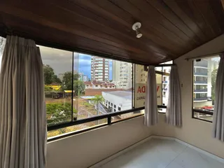 Vista da sala com grandes janelas que oferecem uma visão da paisagem urbana.