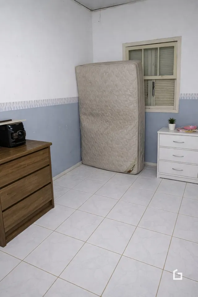 Interior de um cômodo com paredes brancas e piso de cerâmica.
