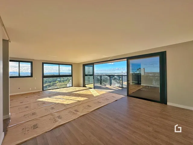 Sala de estar ampla com piso de madeira e vista panorâmica da cidade.