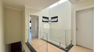 Hall de entrada com piso de madeira e guarda-corpo de vidro.