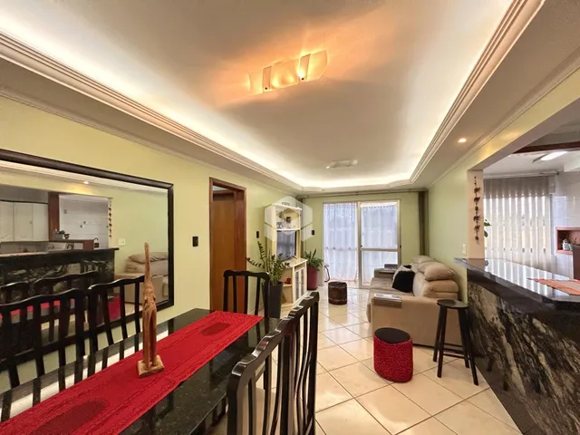 Vista de uma sala de jantar com mesa escura e reflexo de uma área de estar.