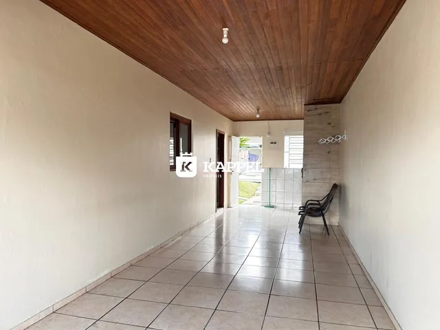Vista de um corredor interno com piso de cerâmica e teto de madeira.