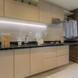 Foto da cozinha com armários claros e bancada escura.