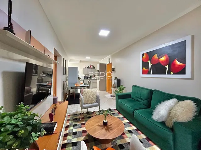 Sala de estar com sofá verde e piso de madeira em um imóvel em Lajeado.