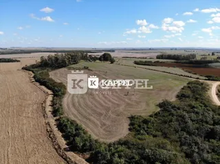 Vista aérea de uma área rural aberta com campos secos e vegetação.