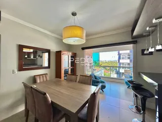 Sala de jantar com mesa de madeira e portas de vidro que dão vista para o exterior.