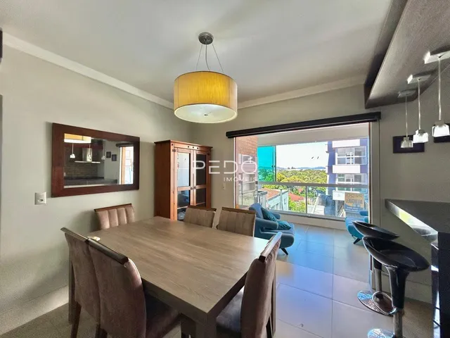 Sala de jantar com mesa de madeira e portas de vidro que dão vista para o exterior.