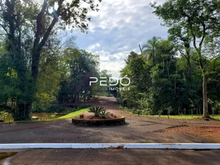 A vista externa da propriedade mostra vegetação densa e uma estrada de terra.