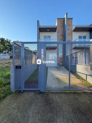 Foto da fachada de uma casa moderna em Lajeado, Brasil, vista através de um portão de metal.