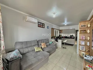 Sala de estar com sofá cinza e cozinha ao fundo.