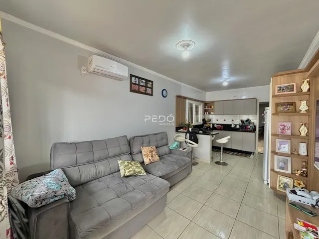 Sala de estar com sofá cinza e cozinha ao fundo.