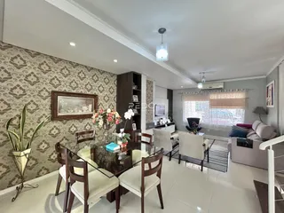 Uma sala de jantar com mesa de madeira escura e decoração de parede em padrão.