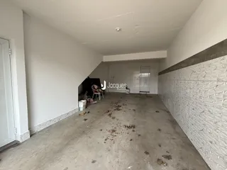 Um corredor interno com piso de concreto e paredes brancas.