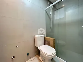 Foto de um banheiro com paredes claras e box de vidro.