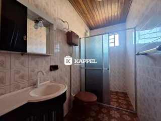 Banheiro com revestimento de azulejos brancos e bancada de pia escura.