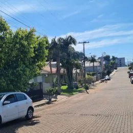 Vista da rua em Lajeado, Brasil com vegetação e um carro estacionado.
