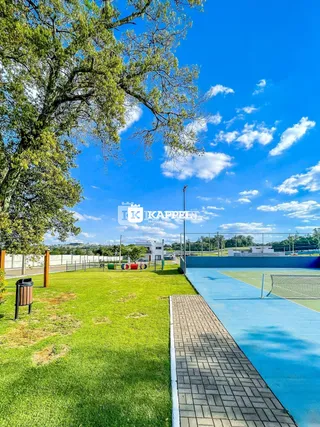 Foto de uma área externa com gramado e quadra de tênis.