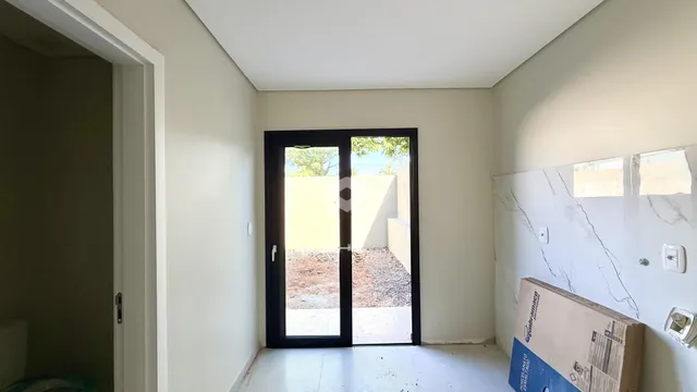 Interior de uma sala com porta de vidro abrindo para o exterior.