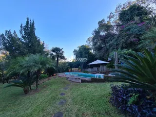 Vista externa de uma área gramada com piscina e vegetação.