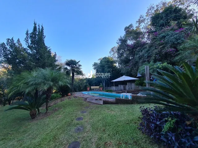 Vista externa de uma área gramada com piscina e vegetação.