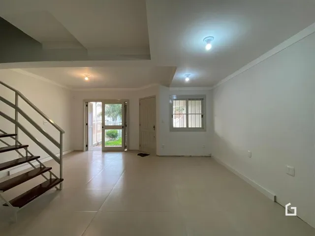 Hall com escada e porta de saída em ambiente residencial.