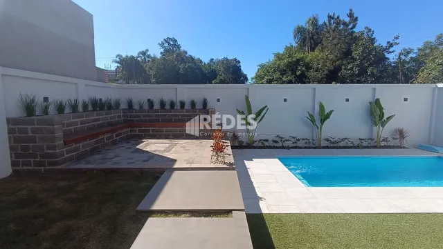 Vista externa mostrando uma piscina e jardim ao lado de uma parede de alvenaria.