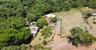 Vista aérea de um terreno rural com vegetação densa e estruturas.